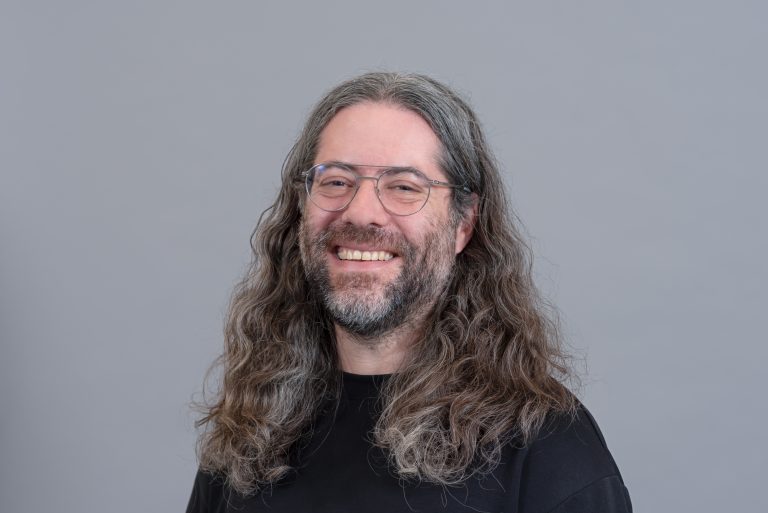 A man with long greying hair poses