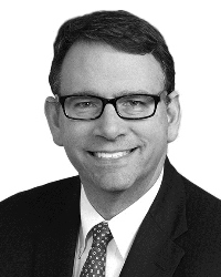 A man with glasses stares at the camera