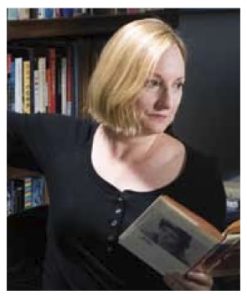 A woman with a black shirt holds a book open