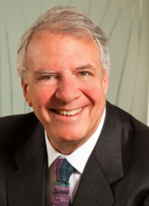 A man with gray hair smiles into the camera