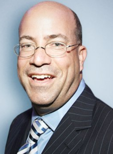 A man with glasses smiles at the camera