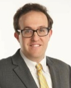 A man with glasses smiles at the camera