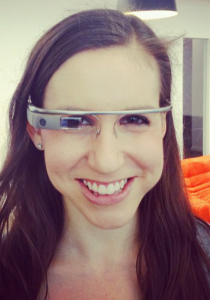 A woman with glasses smiles at the camera