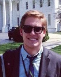 Man in sunglasses smiles in front of the White House