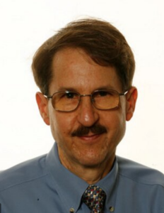 A man with glasses looks into the camera