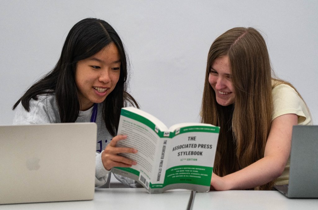 Two people read an AP Stylebook.