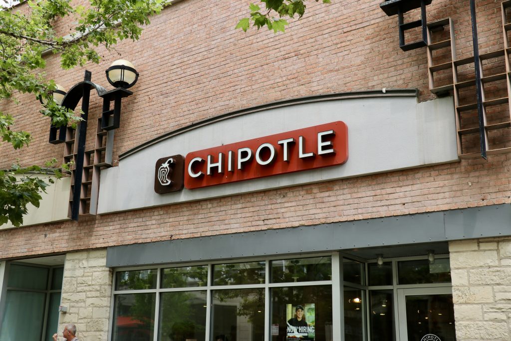 A Chipotle sign hangs on a red brick building.