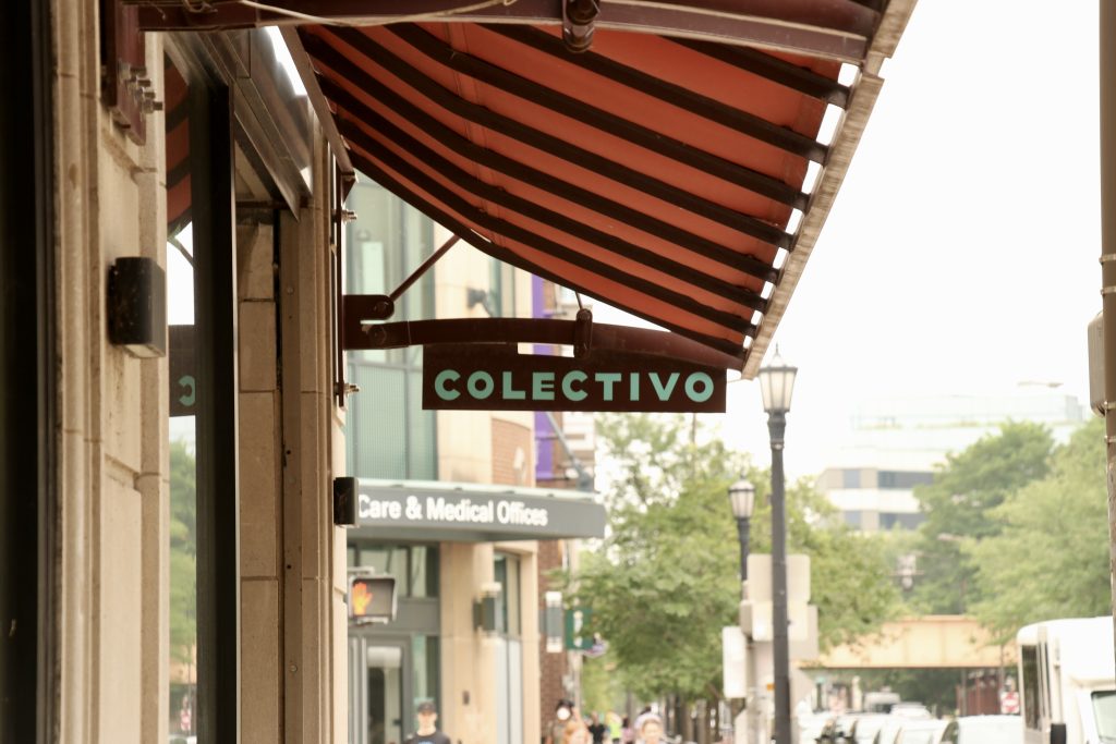 A sign hangs from a store awning.