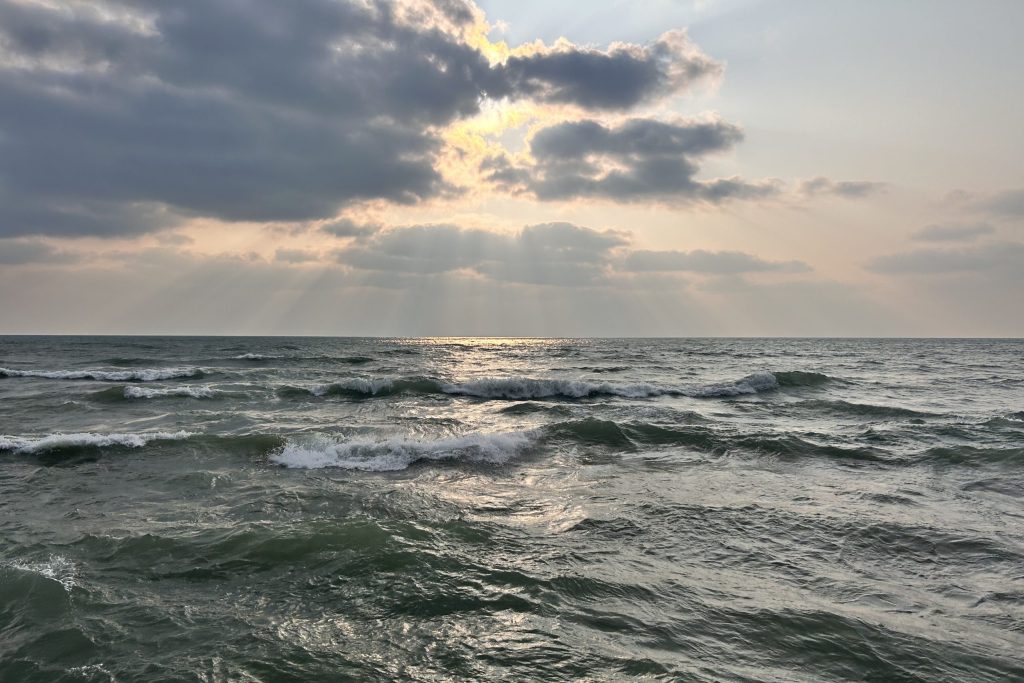 The sun rises above waves.