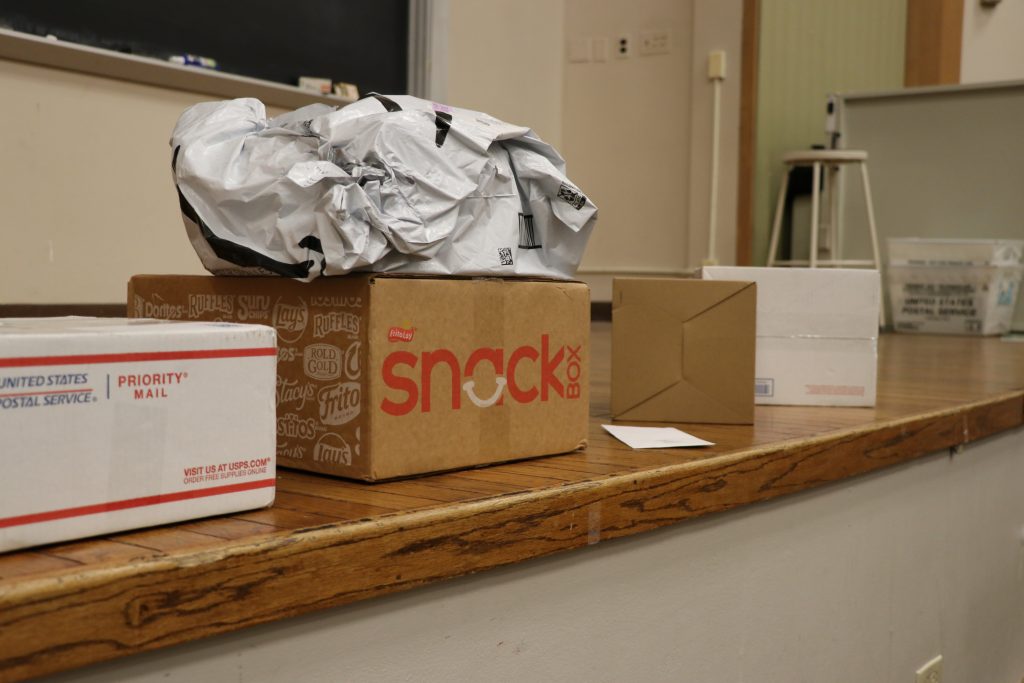 Five packages sit on a stage. One package is on top of another.