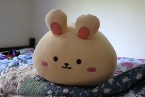 A bunny stuffed animal rests on a bed.