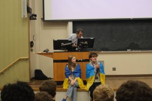 Two people sit on a stage.