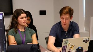 Three people look at a laptop.